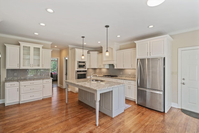 kitchen with white cabinets, a kitchen breakfast bar, stainless steel appliances, light wood-style floors, and a sink