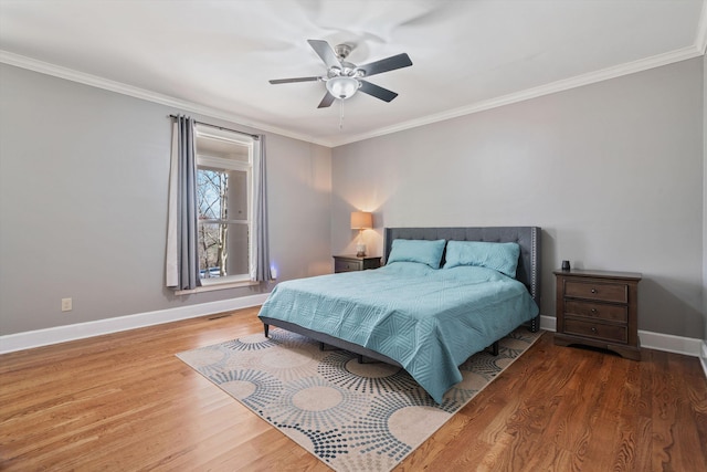 bedroom featuring ceiling fan, wood finished floors, visible vents, baseboards, and ornamental molding