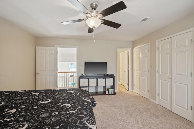 bedroom with ceiling fan, carpet flooring, visible vents, and multiple closets