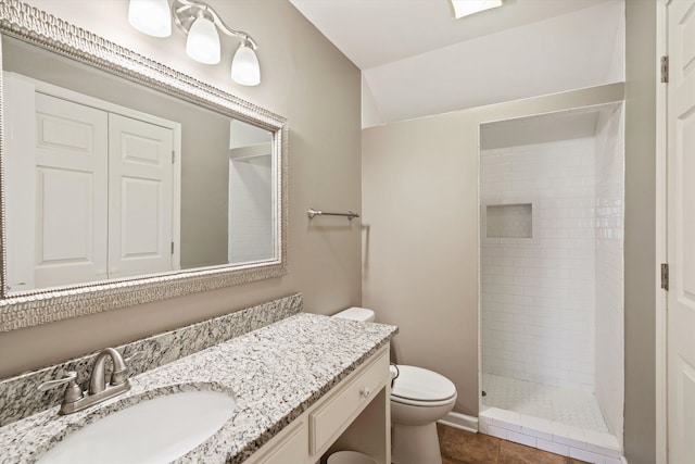 full bathroom with lofted ceiling, toilet, vanity, a tile shower, and tile patterned floors