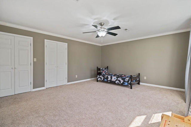 carpeted bedroom with multiple closets, visible vents, ornamental molding, ceiling fan, and baseboards