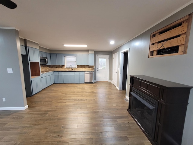 kitchen featuring stainless steel appliances, dark wood finished floors, ornamental molding, and tasteful backsplash