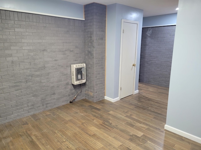 bathroom with brick wall, baseboards, heating unit, and wood finished floors