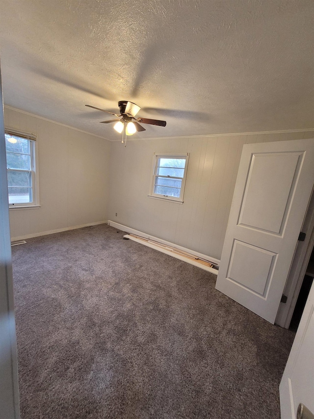 unfurnished bedroom with a textured ceiling, ceiling fan, multiple windows, and carpet flooring