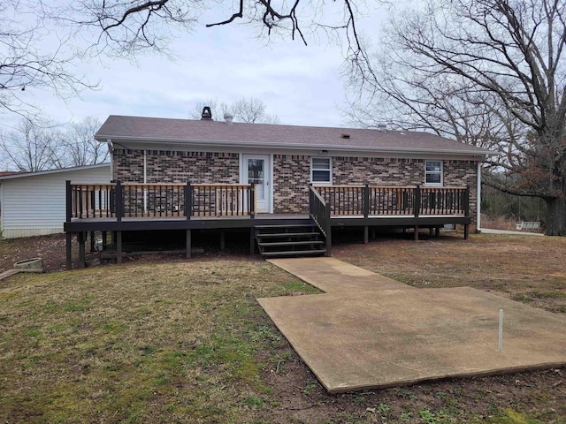 back of property with brick siding, a lawn, and a wooden deck