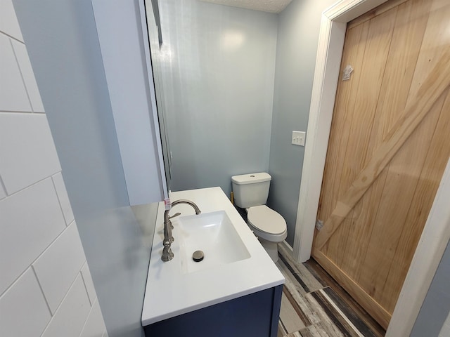 bathroom featuring vanity, toilet, and wood finished floors