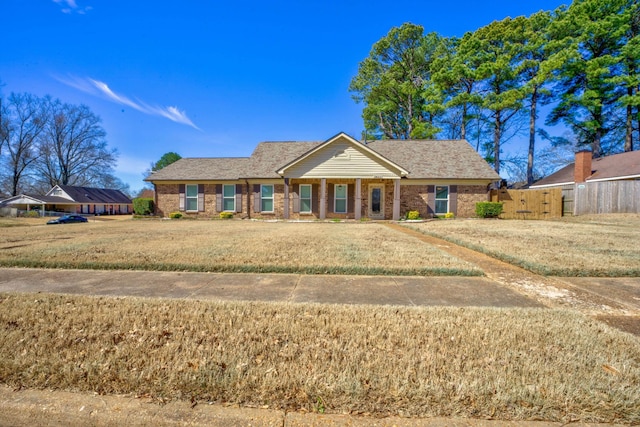 view of front of house featuring a front yard, brick siding, and fence