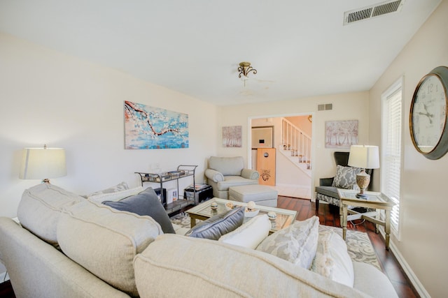 living room with stairs, wood finished floors, visible vents, and baseboards