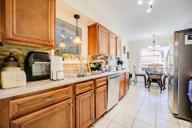 kitchen with light tile patterned floors, decorative backsplash, stainless steel appliances, light countertops, and a sink