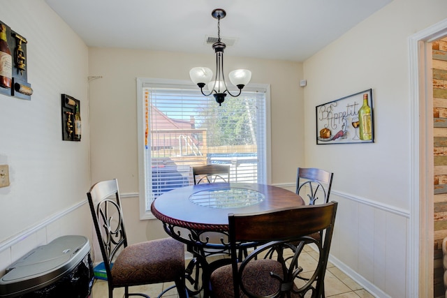 dining area with light tile patterned floors, wainscoting, visible vents, and an inviting chandelier