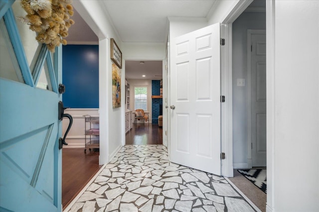 hallway featuring ornamental molding, light wood finished floors, and baseboards