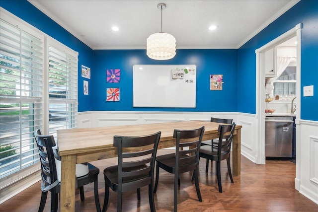 dining room with dark wood-style floors, a notable chandelier, crown molding, and wainscoting