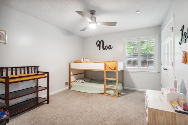 carpeted bedroom featuring a textured ceiling, ceiling fan, visible vents, and baseboards