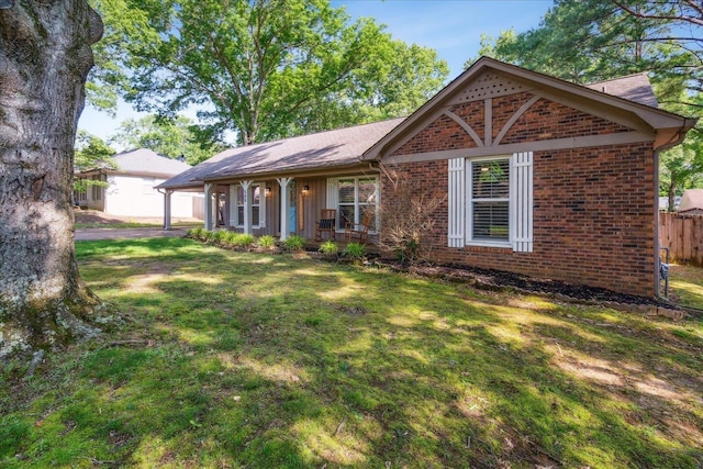 ranch-style home with brick siding, a porch, a front yard, and fence