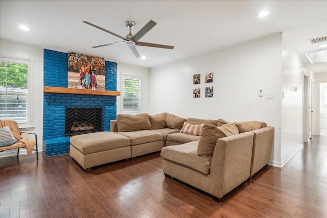 living area with visible vents, attic access, a ceiling fan, a brick fireplace, and wood finished floors