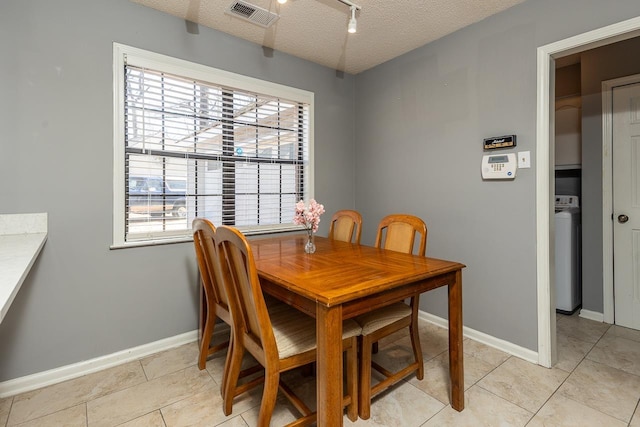 dining area with washer / dryer, light tile patterned floors, baseboards, visible vents, and a textured ceiling