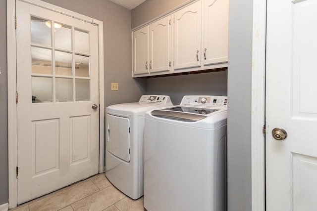 laundry area featuring light tile patterned floors, washing machine and clothes dryer, and cabinet space