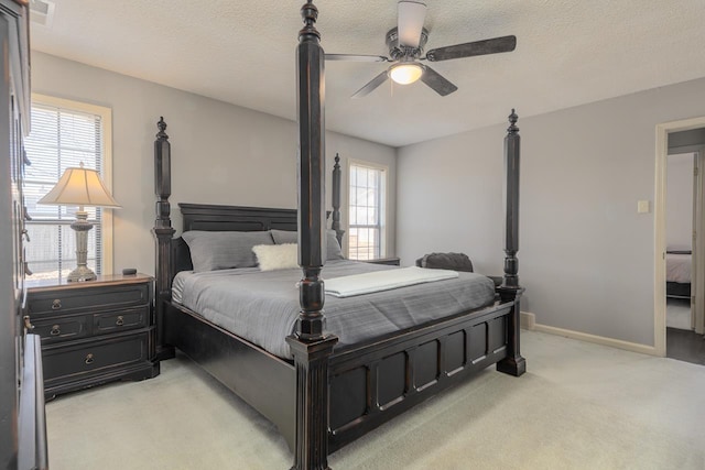 bedroom featuring light colored carpet, visible vents, a ceiling fan, a textured ceiling, and baseboards