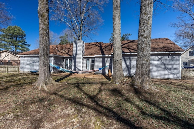 back of house with a yard, fence, and a chimney