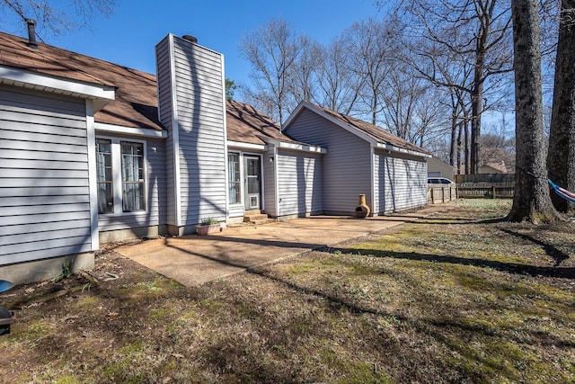 view of side of property featuring entry steps, a chimney, and fence