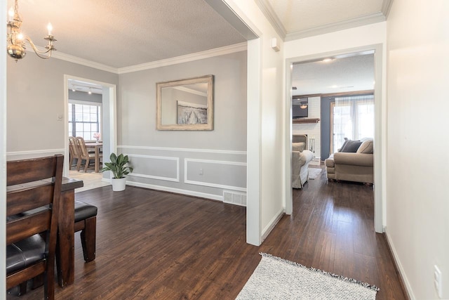 hall with dark wood-type flooring, crown molding, and a textured ceiling