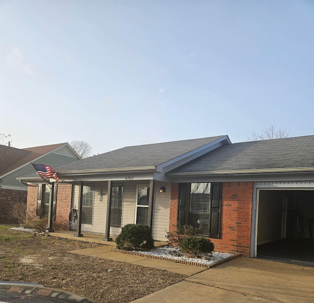 single story home with a porch, brick siding, an attached garage, and roof with shingles