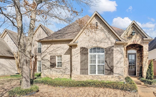 french country home with brick siding and roof with shingles