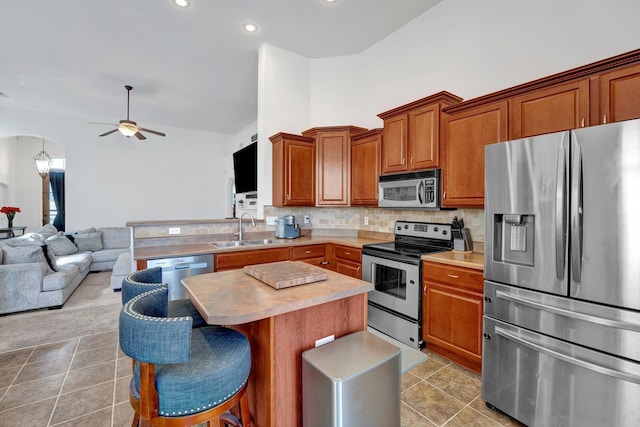 kitchen with arched walkways, backsplash, appliances with stainless steel finishes, open floor plan, and a sink