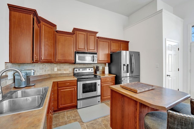 kitchen featuring a breakfast bar area, a sink, appliances with stainless steel finishes, backsplash, and a center island