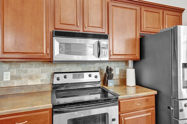 kitchen featuring brown cabinets, appliances with stainless steel finishes, decorative backsplash, and light countertops