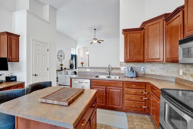 kitchen with ceiling fan, appliances with stainless steel finishes, brown cabinets, a sink, and backsplash