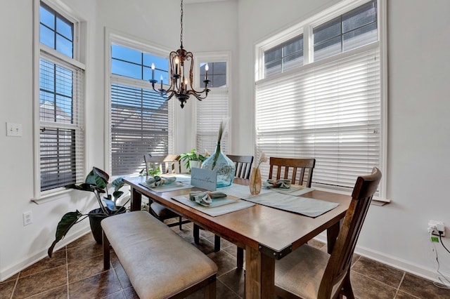 dining area with baseboards, dark tile patterned floors, and a notable chandelier