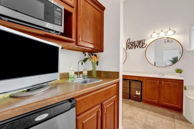 kitchen with light tile patterned floors, appliances with stainless steel finishes, brown cabinetry, and a sink