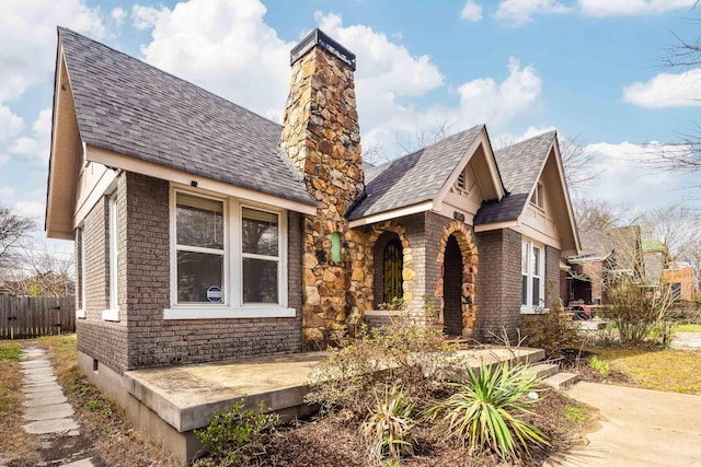 view of front of property with roof with shingles, a chimney, and fence