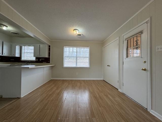 interior space featuring a textured ceiling, wood finished floors, and crown molding