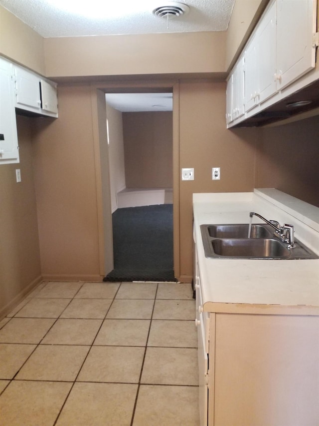 kitchen featuring light tile patterned floors, light countertops, visible vents, white cabinets, and a sink