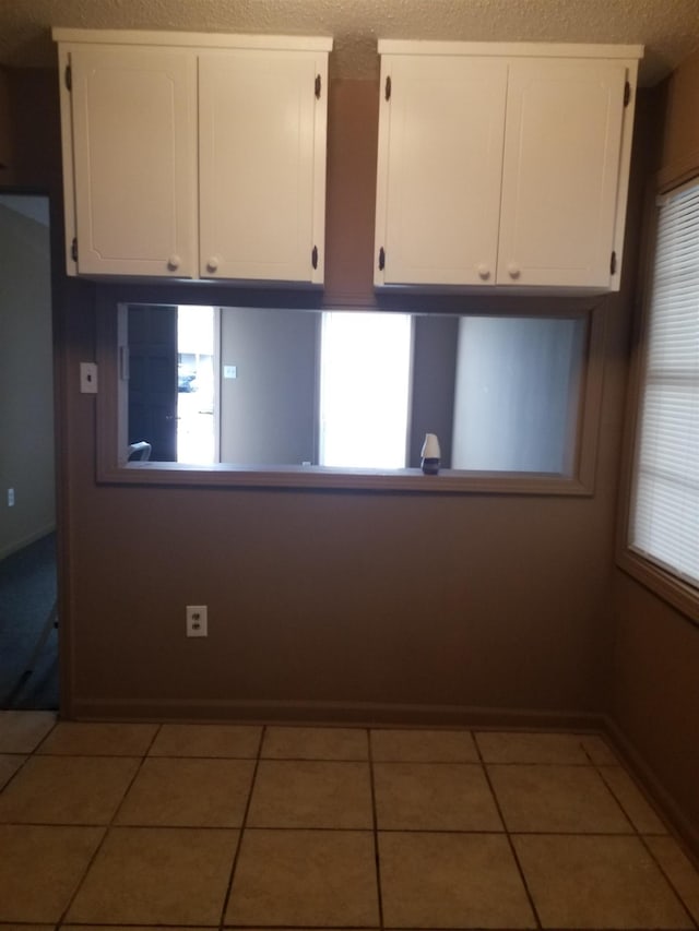 unfurnished room featuring a textured ceiling, baseboards, and tile patterned floors