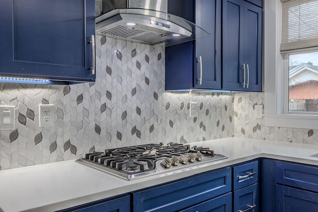 kitchen featuring stainless steel gas cooktop, tasteful backsplash, ventilation hood, and blue cabinets