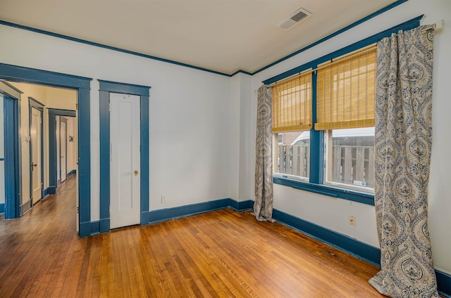 spare room featuring hardwood / wood-style floors, visible vents, and baseboards