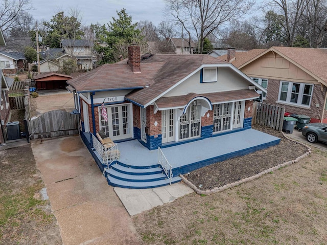 bungalow with central AC unit, a chimney, a gate, fence, and brick siding