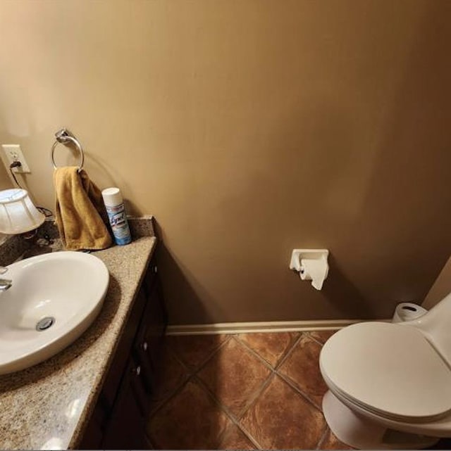 bathroom with toilet, tile patterned flooring, vanity, and baseboards