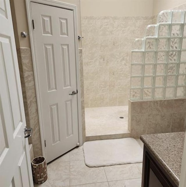 full bath with tile patterned flooring, walk in shower, tile walls, and vanity