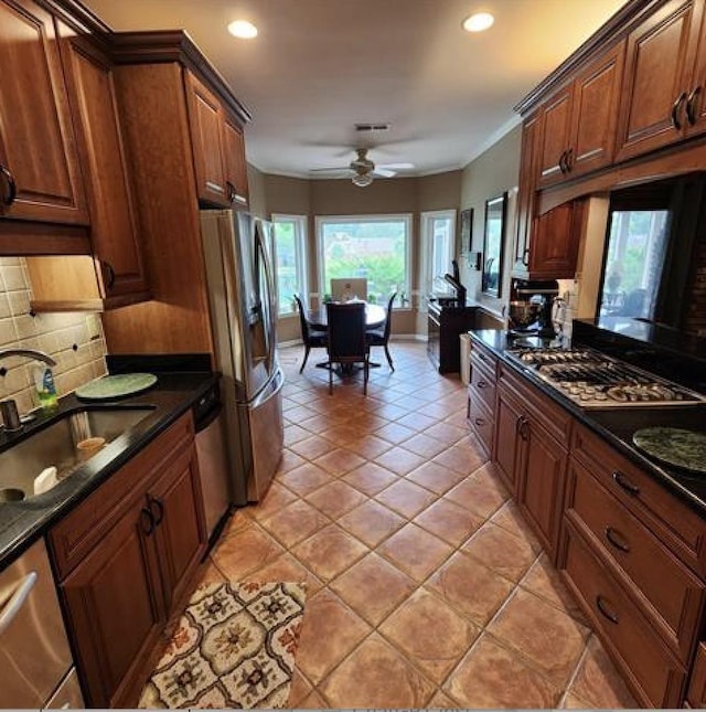 kitchen featuring dark countertops, ceiling fan, appliances with stainless steel finishes, a sink, and backsplash