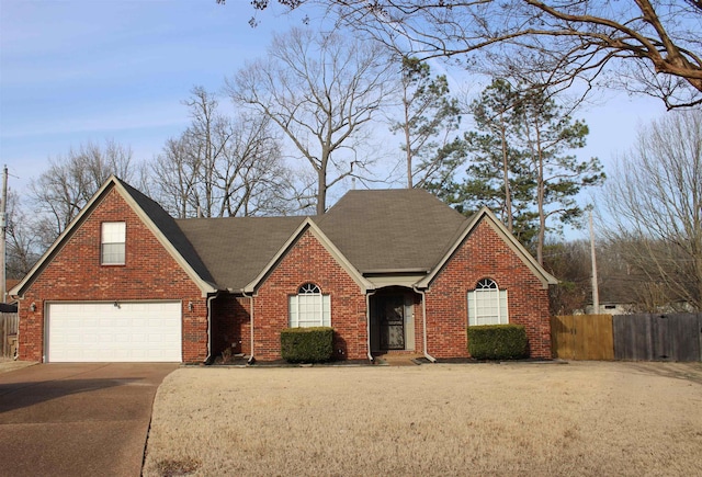 traditional-style home with an attached garage, fence, concrete driveway, and brick siding