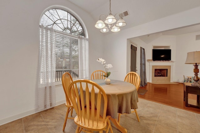 dining area with visible vents, an inviting chandelier, a fireplace with flush hearth, light tile patterned flooring, and baseboards