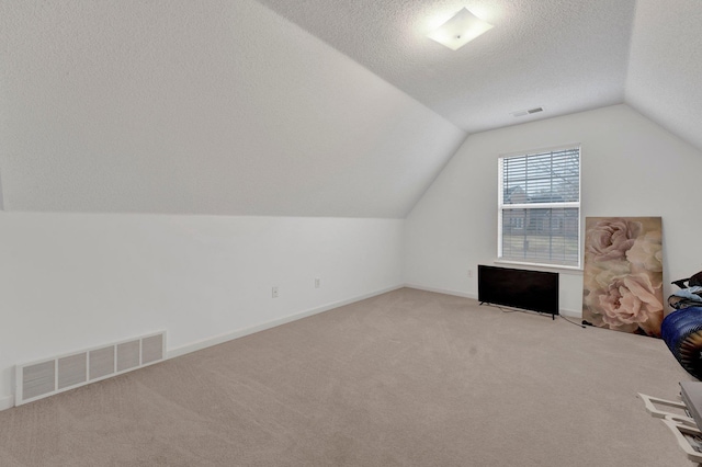 bonus room featuring light colored carpet, visible vents, vaulted ceiling, and a textured ceiling