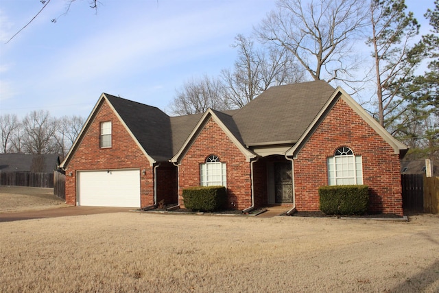 traditional-style home with a garage, driveway, fence, and brick siding