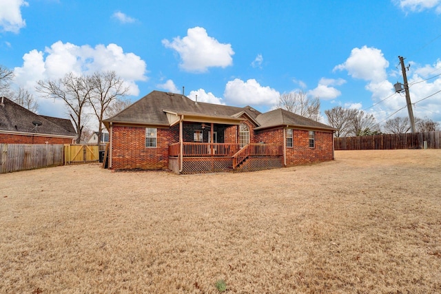 back of house featuring a deck, brick siding, a yard, and a fenced backyard