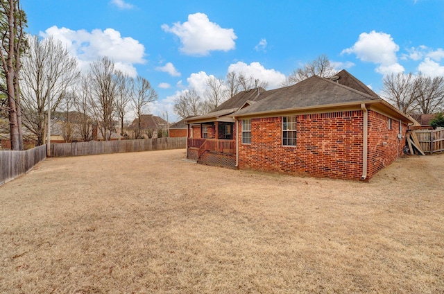 back of house with brick siding, a lawn, and a fenced backyard