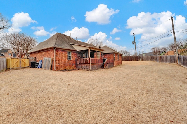 back of property featuring a deck, a yard, brick siding, and a fenced backyard